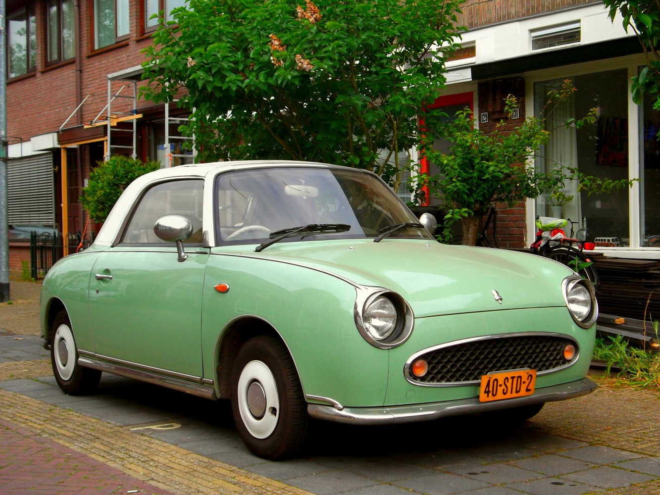 Retro small car with round headlights, mesh grille, and white roof