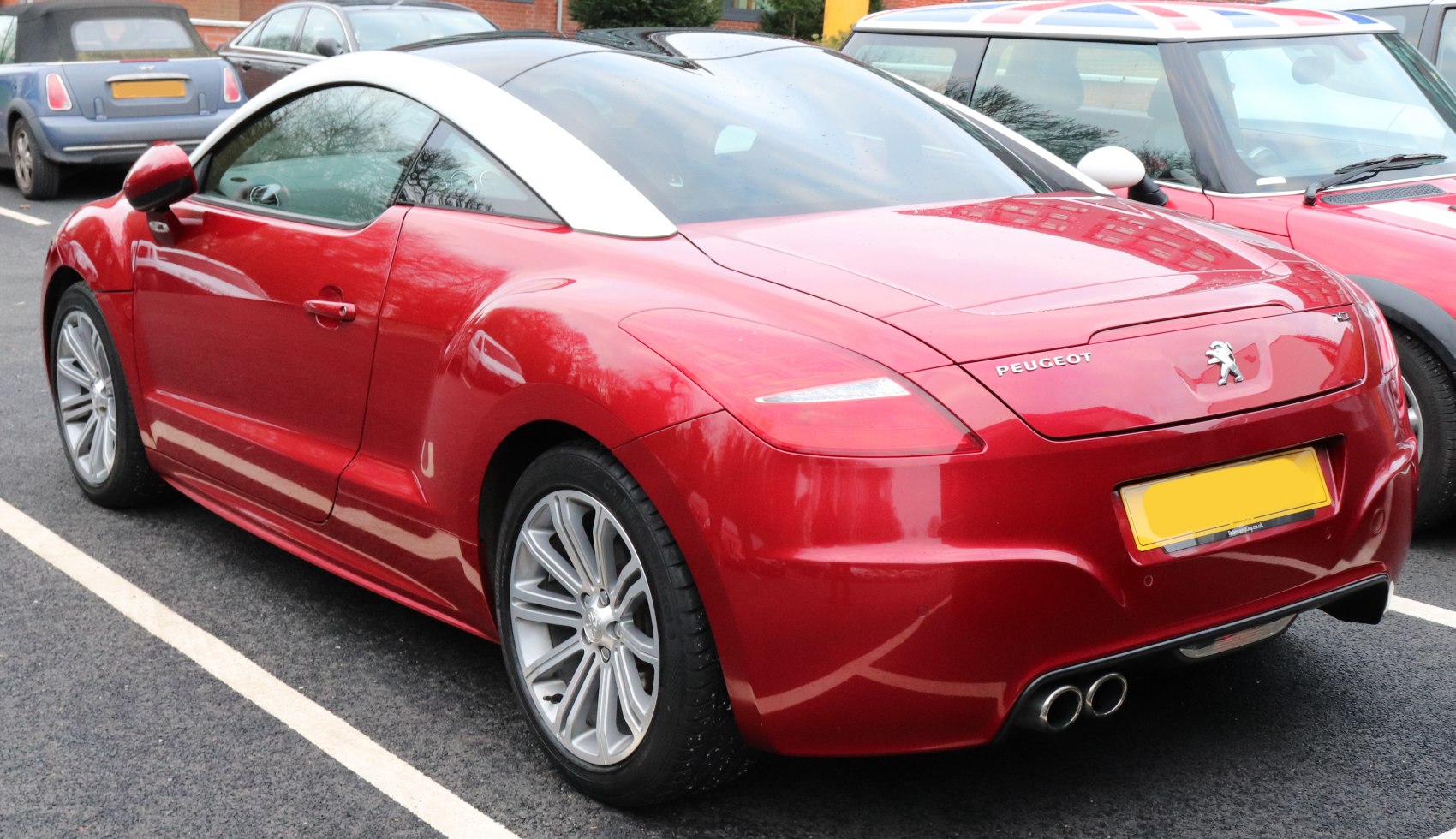 Rear side view of red sports coupe with silver roof arch and dual exhausts
