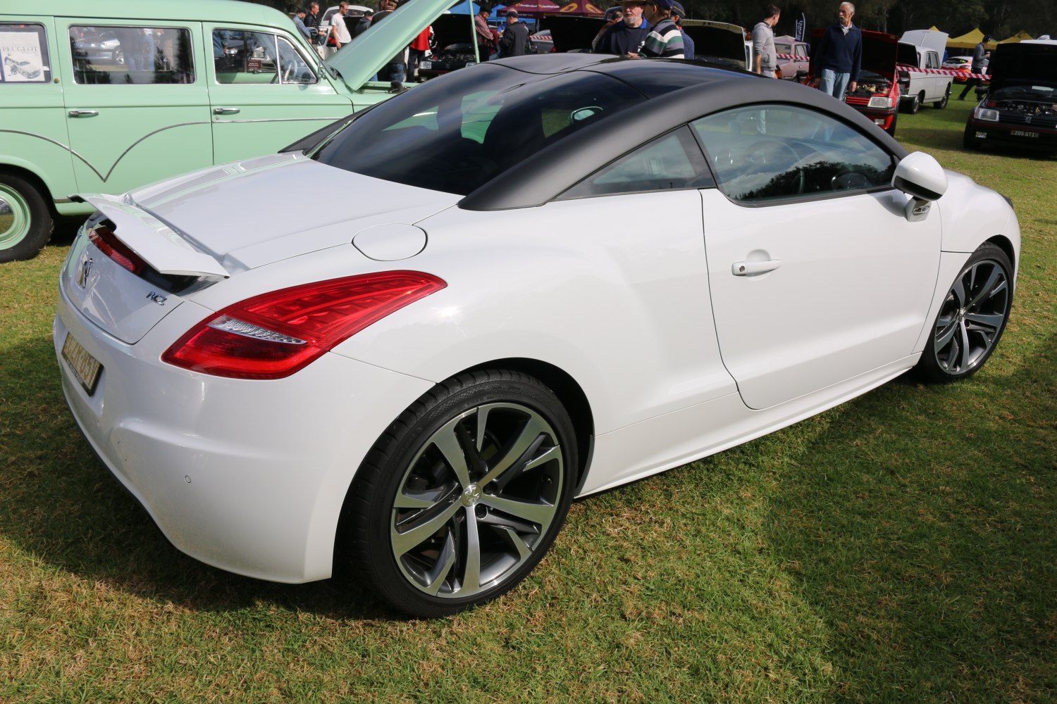 Rear side view of a white coupe with spoiler and distinctive roofline