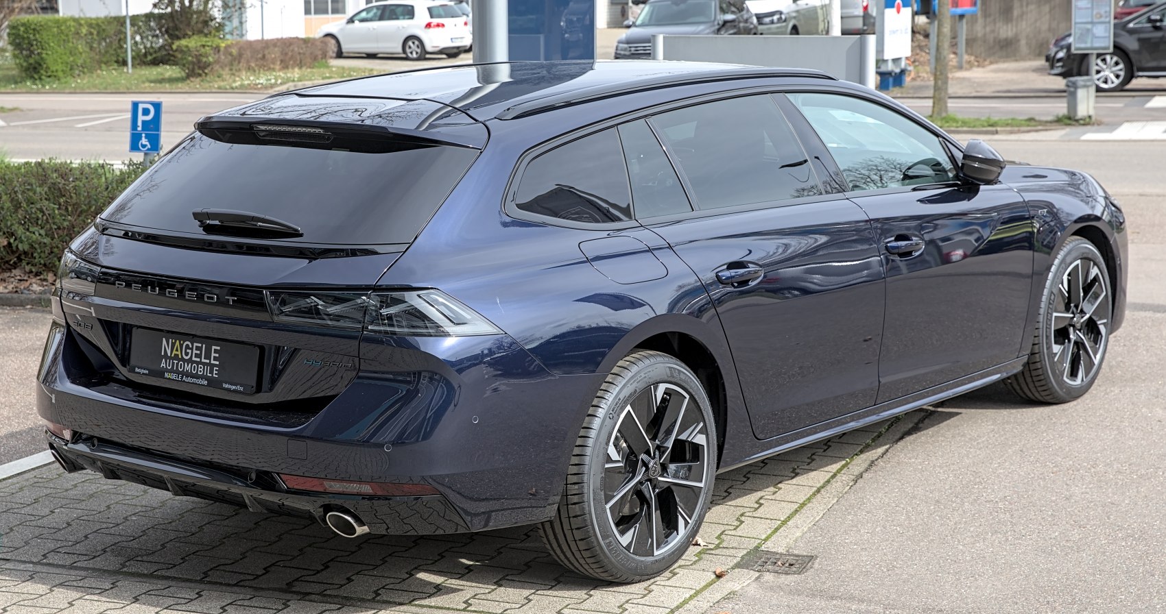 Rear side view of a sleek modern station wagon with tinted windows and hybrid badge