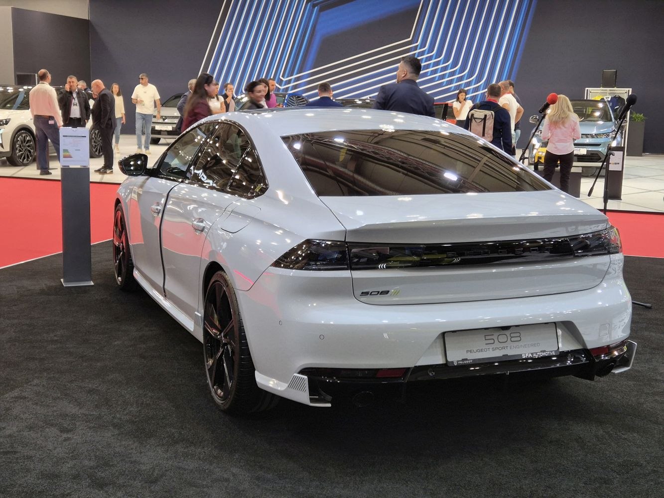 Rear view of sleek sedan with dark tail lights and sporty black wheels.