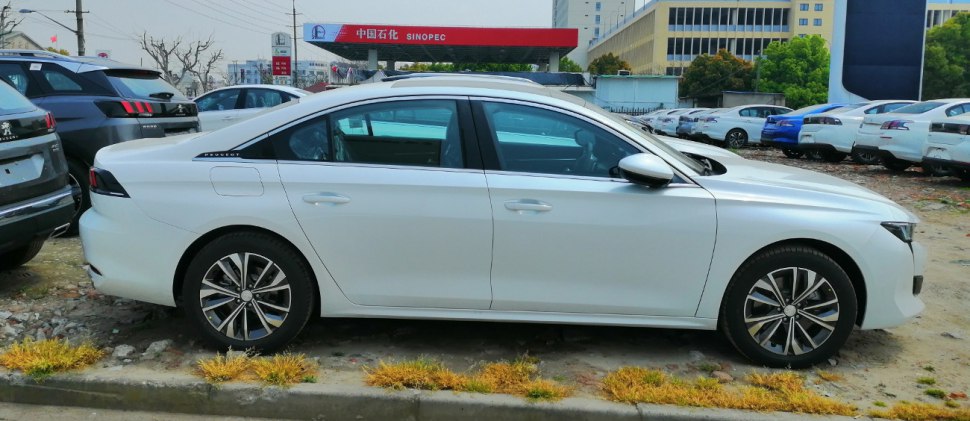 Side profile of a modern sedan with alloy wheels parked outdoors.