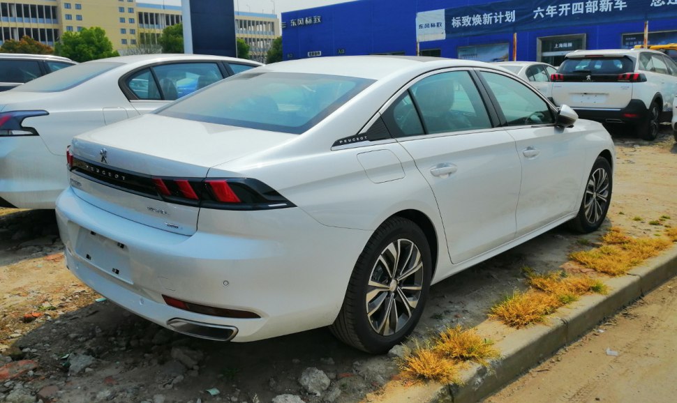 Rear and side profile of a sleek white sedan with distinctive taillights.