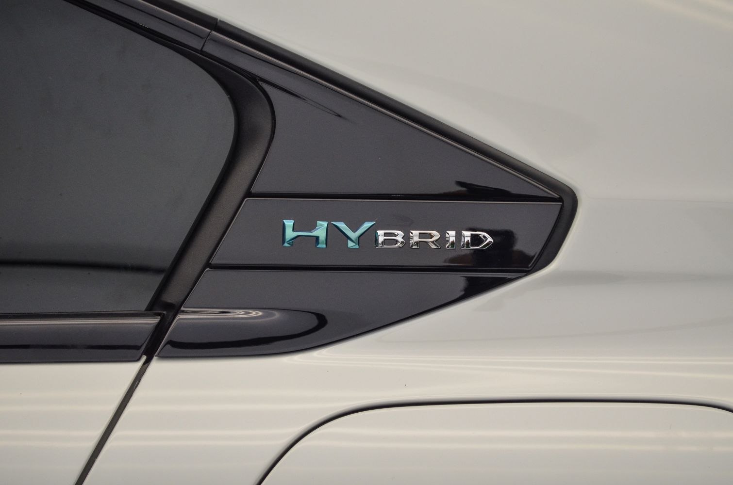 Close-up of hybrid badge on car window trim.