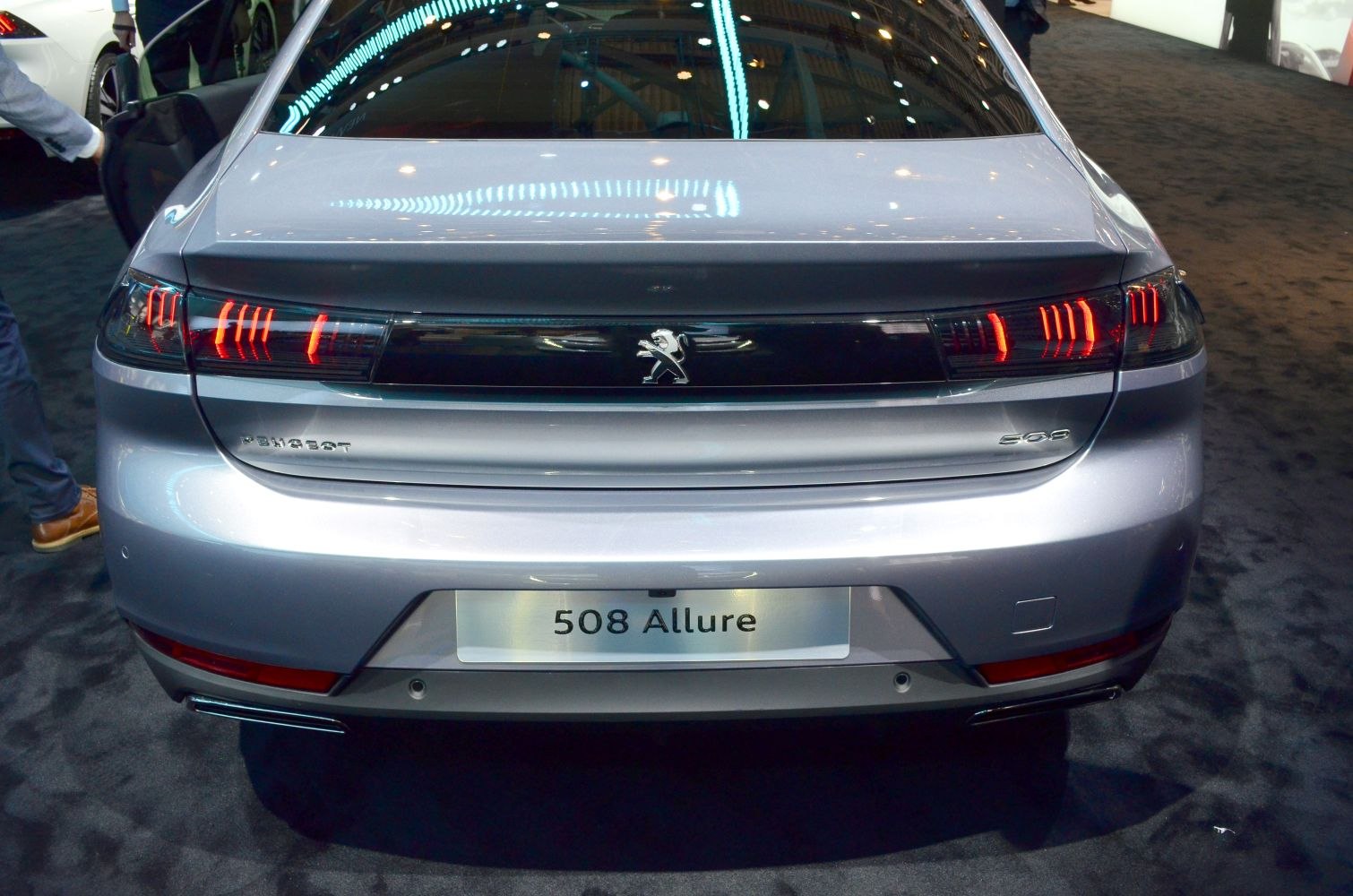 Rear view with illuminated LED taillights and central emblem.
