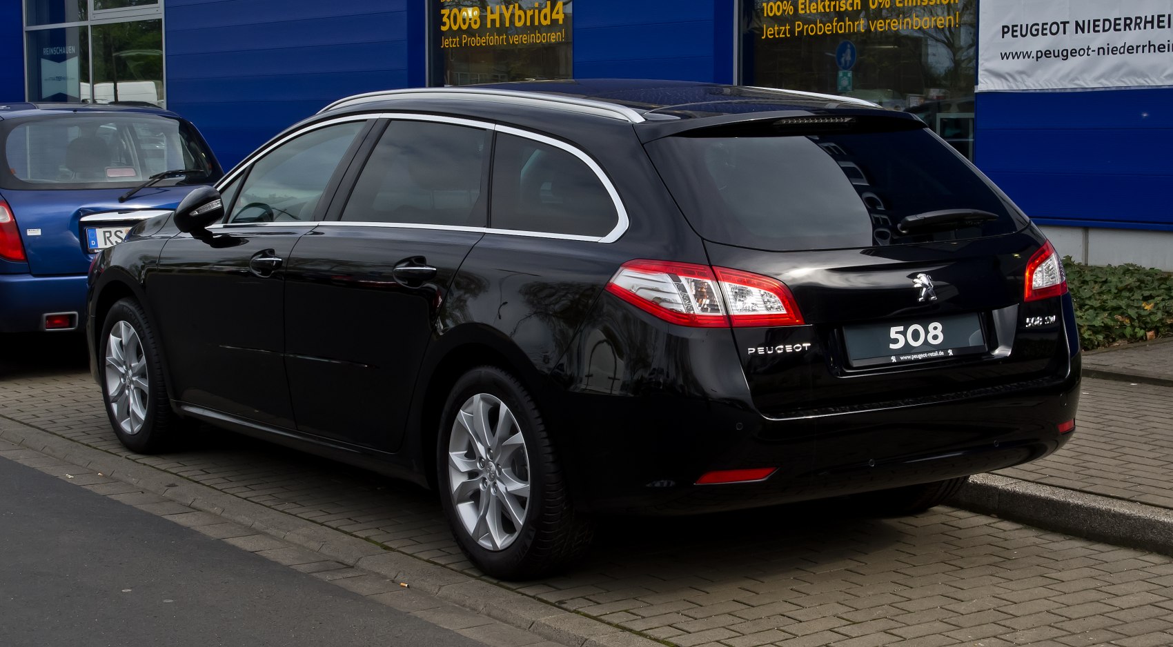 Rear side view of black station wagon with chrome window trim and distinct tail lights