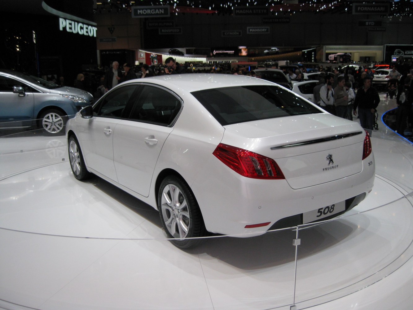 Sleek rear and side view of a white sedan with distinctive taillights and alloy wheels