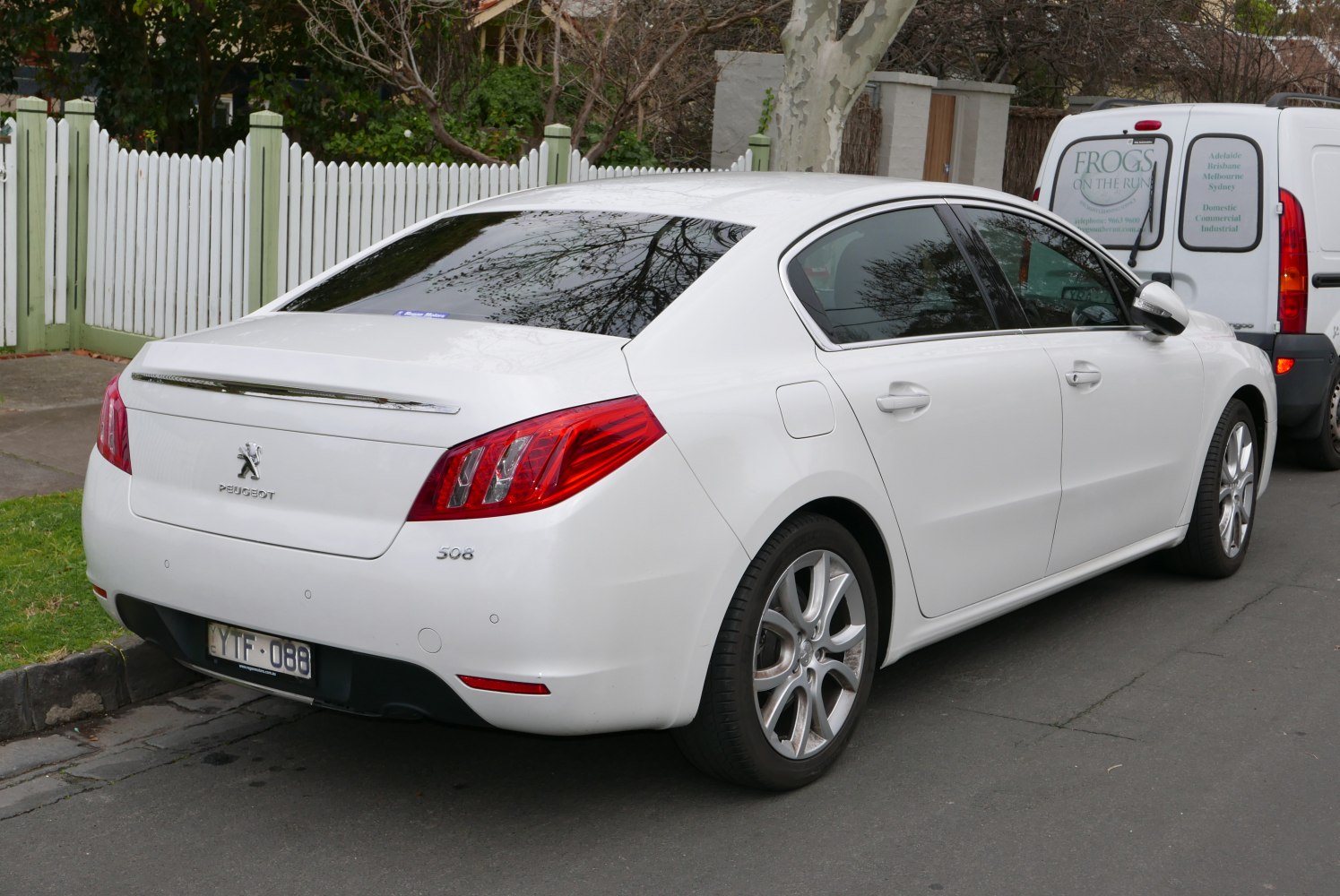 Rear angled white sedan with distinctive tail lights and alloy wheels