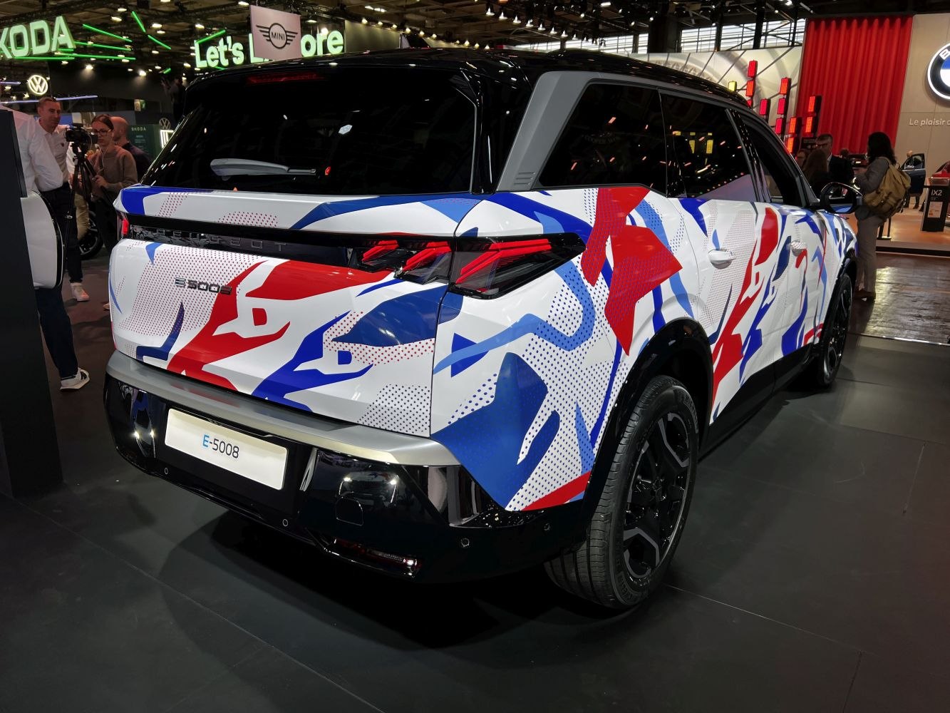 Rear side of SUV with colorful red, blue, and white camouflage wrap and modern taillights