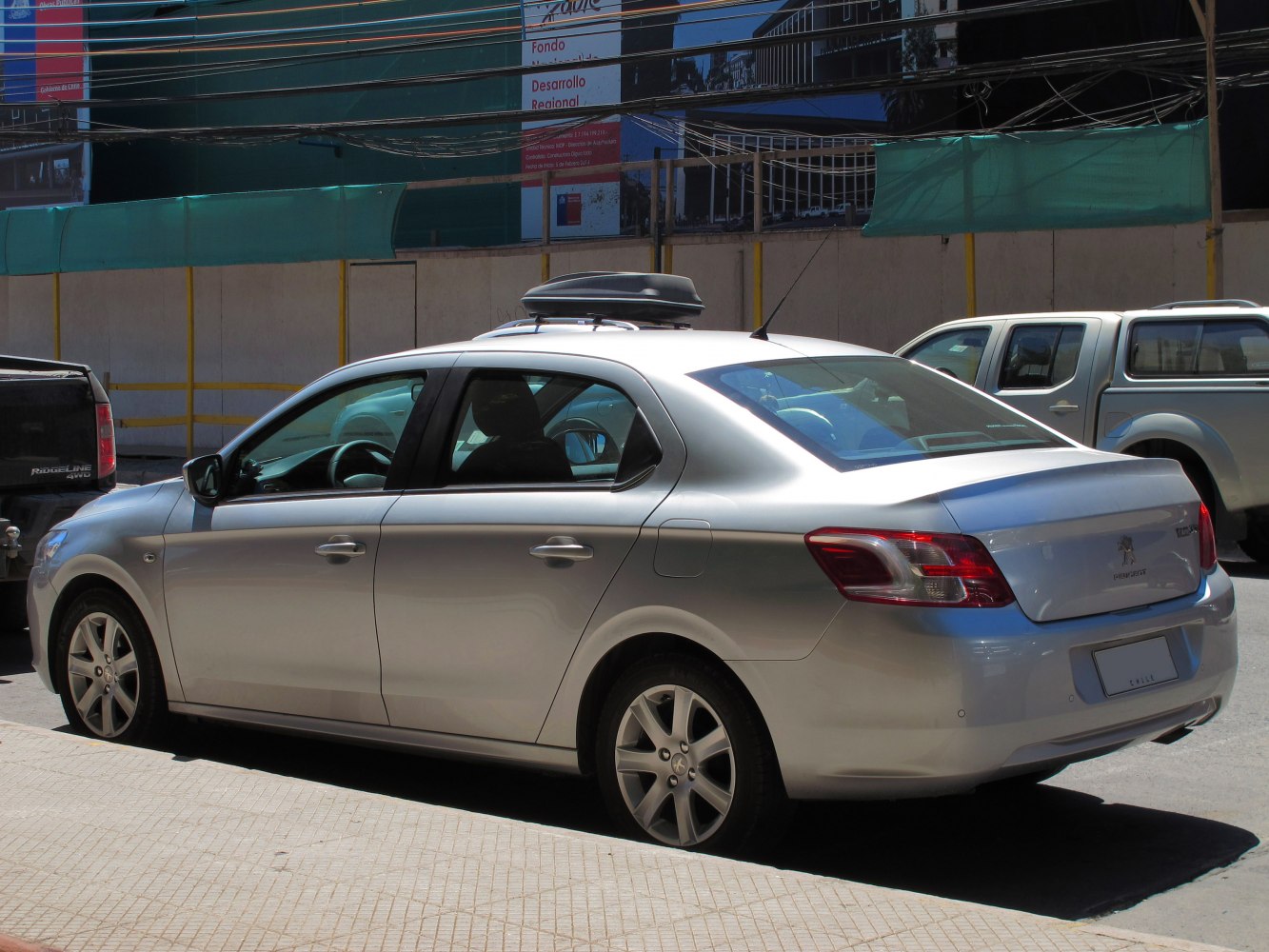 Silver sedan with roof cargo box, sleek design, and modern taillights