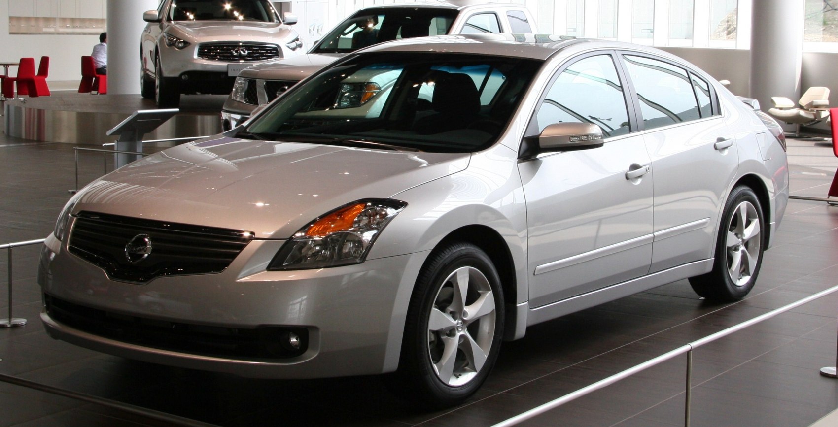 Silver sedan front three-quarter view with alloy wheels in showroom