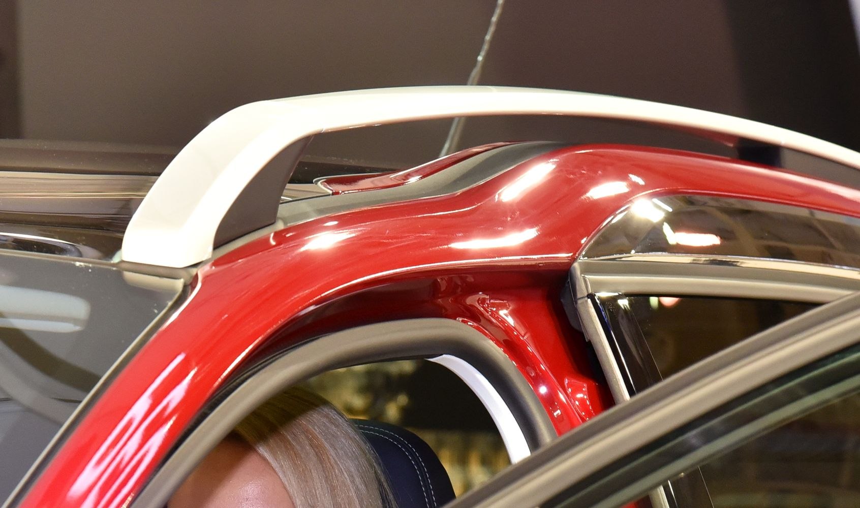 Close-up of red car roof with white roof rail and window trim