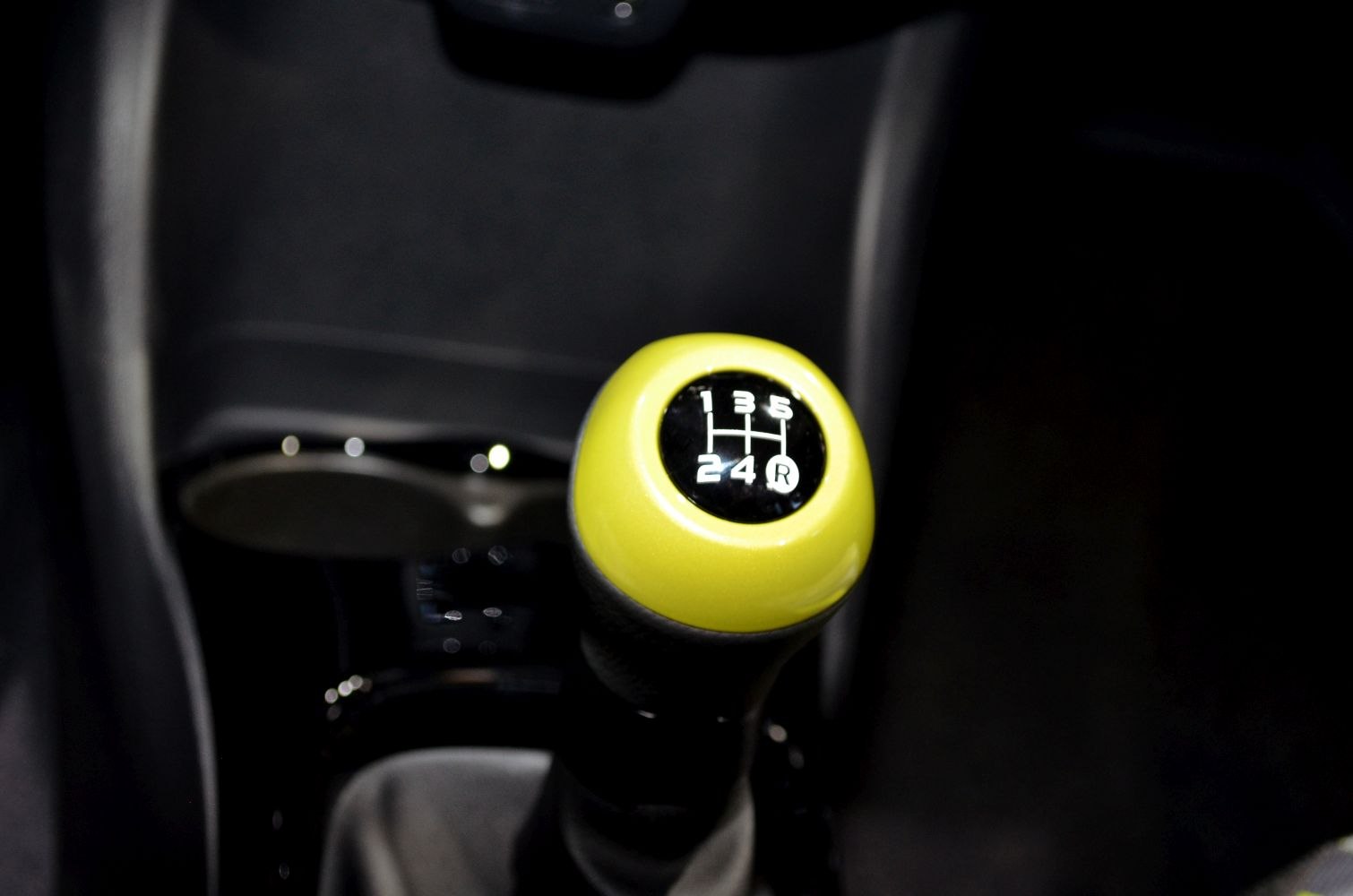 Close-up of a manual 5-speed gear shift knob with yellow top.