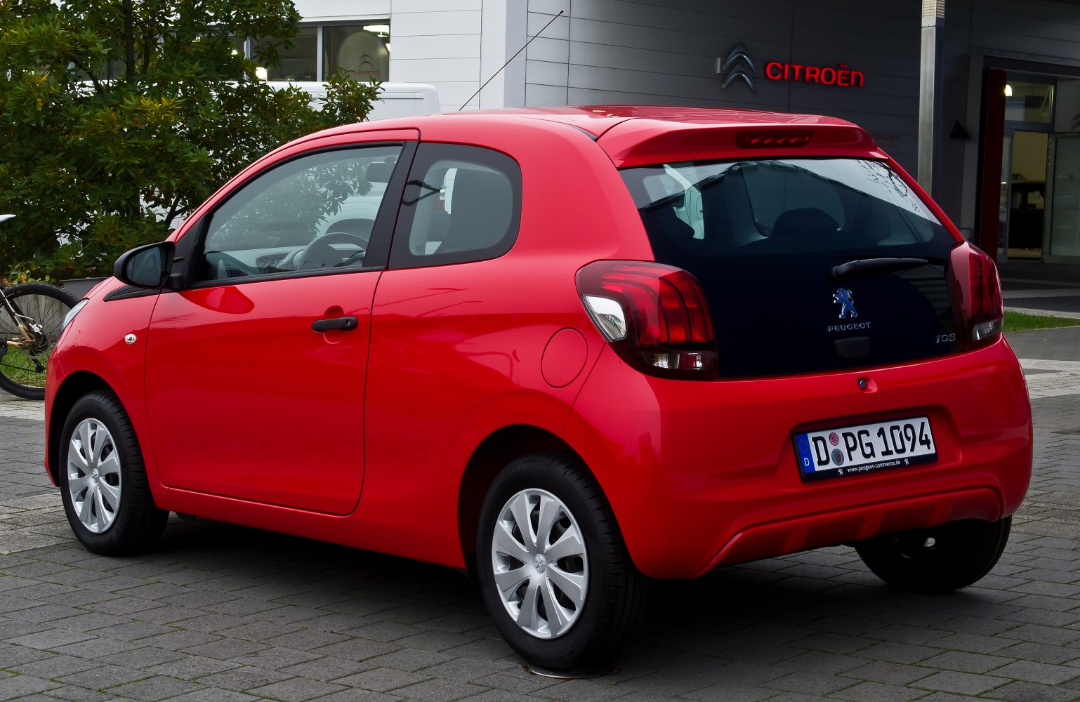 Rear-side view of red compact hatchback with distinctive taillights and small wheels