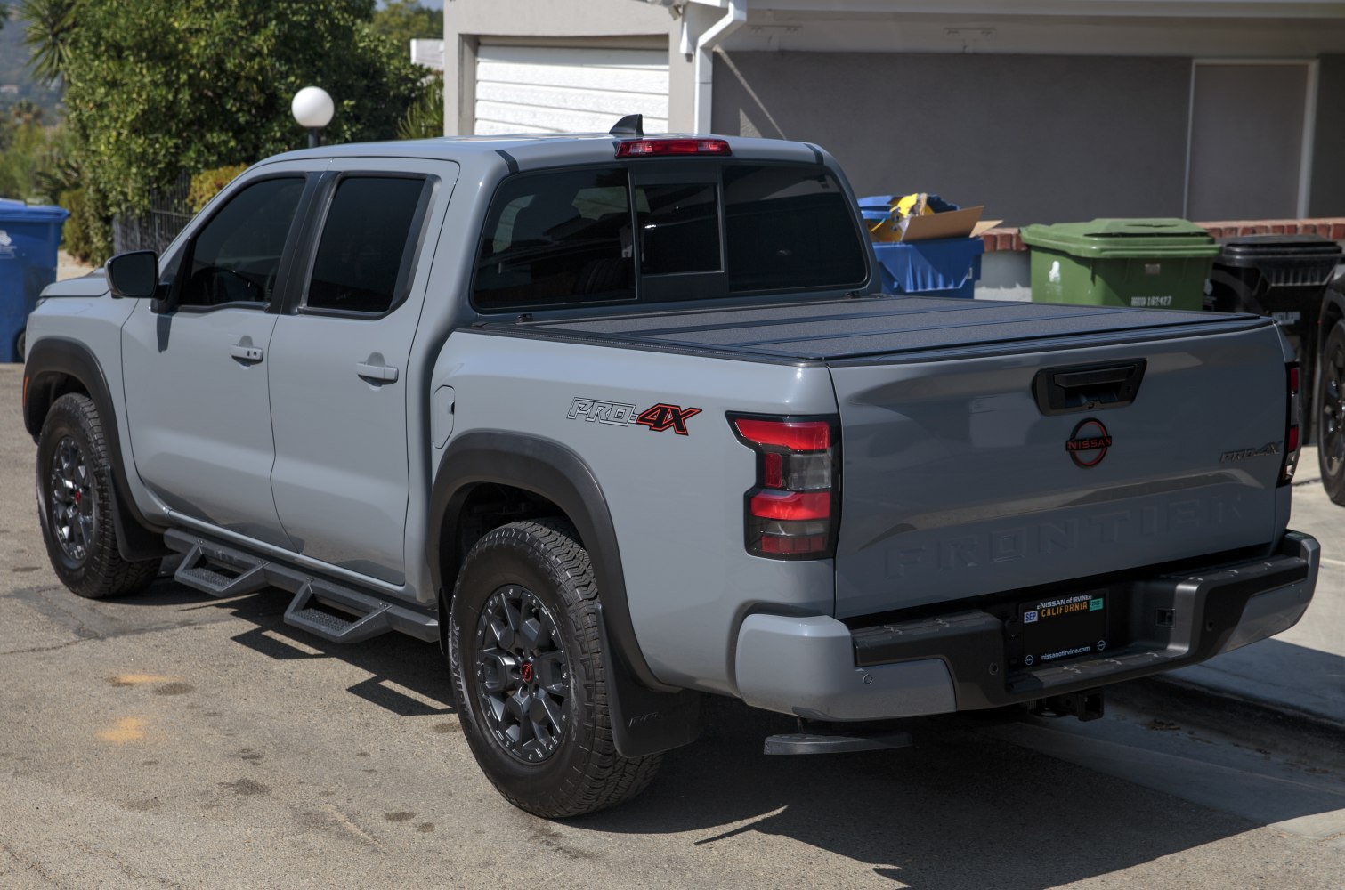 Rear view of a pickup with PRO-4X badge, step rails, and covered bed