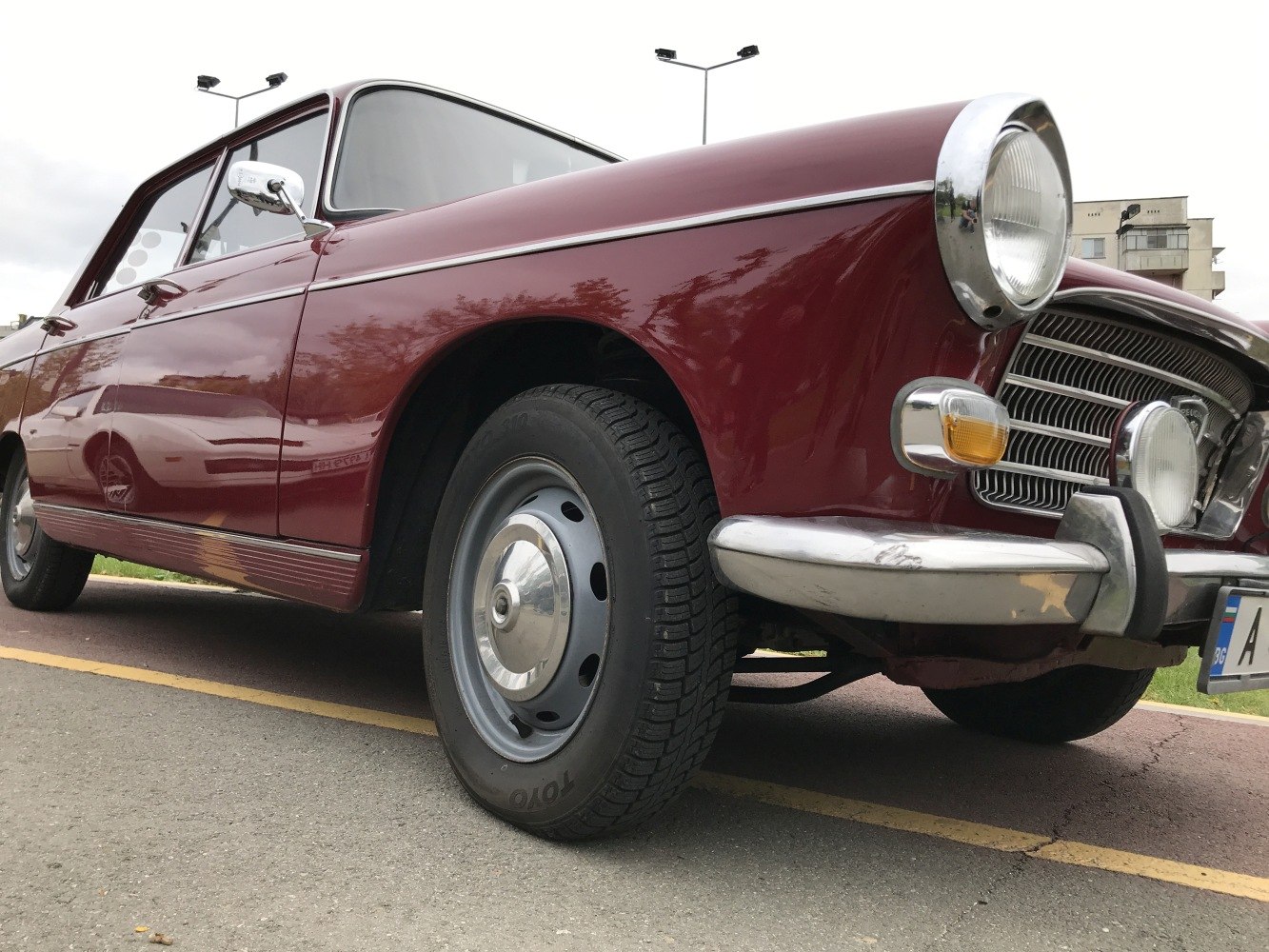 Vintage sedan front with round headlight, chrome bumper, and hubcap wheel