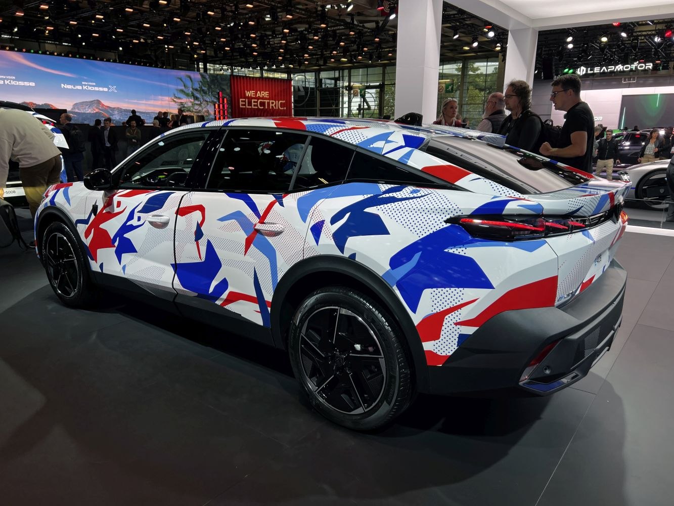 Modern crossover with red, white, and blue geometric wrap and black wheels.