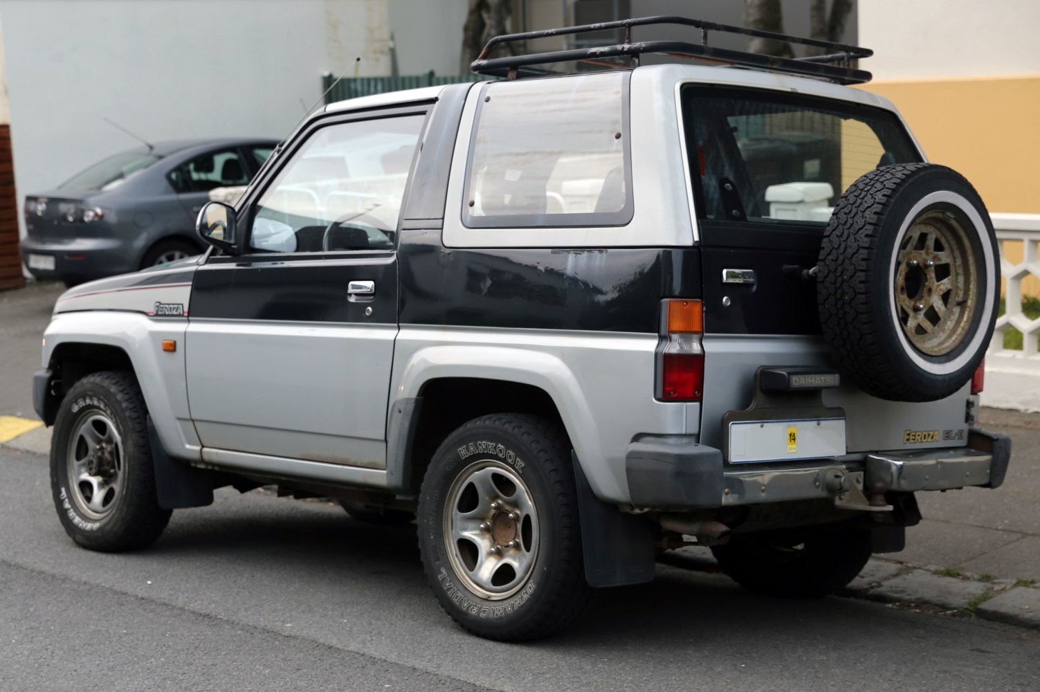 Rear side view of SUV with spare tire mounted on back door and roof rack.