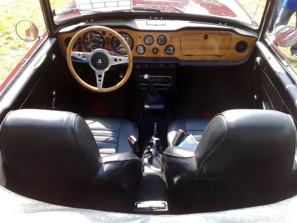 Vintage wooden dashboard and steering wheel with black leather seats.