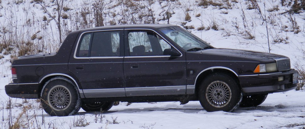 Side profile of a 1989 sedan with mesh wheels and four doors