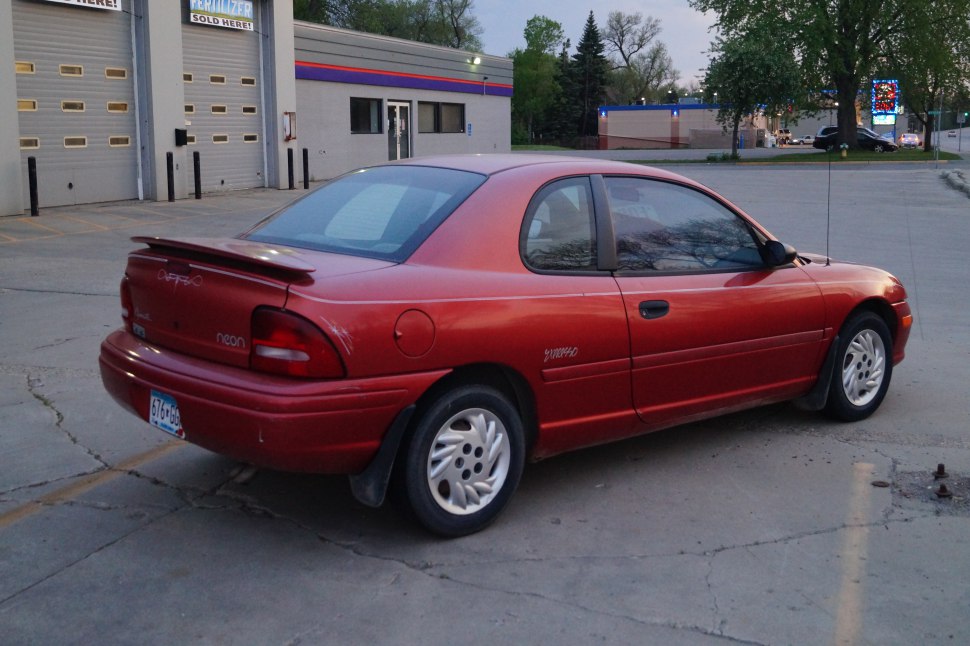 Red 1994 coupe with rear spoiler and hubcap wheels