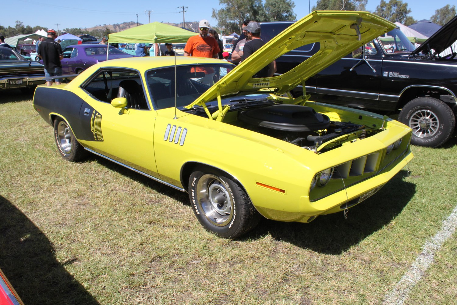 Yellow muscle car with black side stripes and open hood