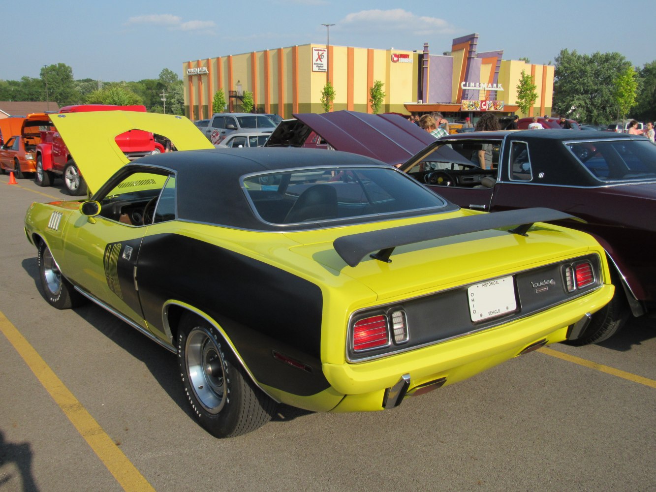 Two-tone muscle car with prominent rear spoiler and open hood.
