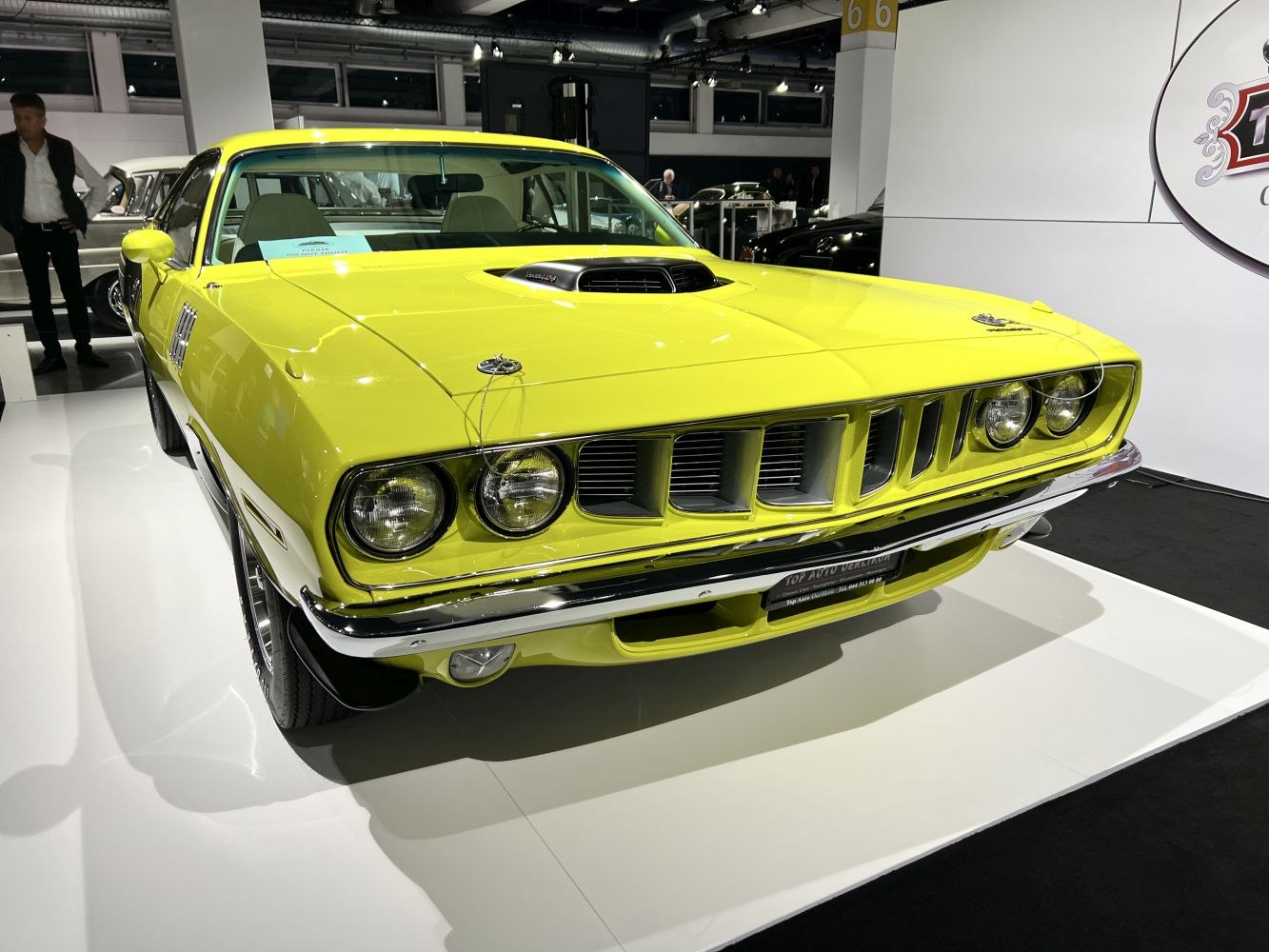 Bright yellow muscle car front with hood scoop and quad round headlights