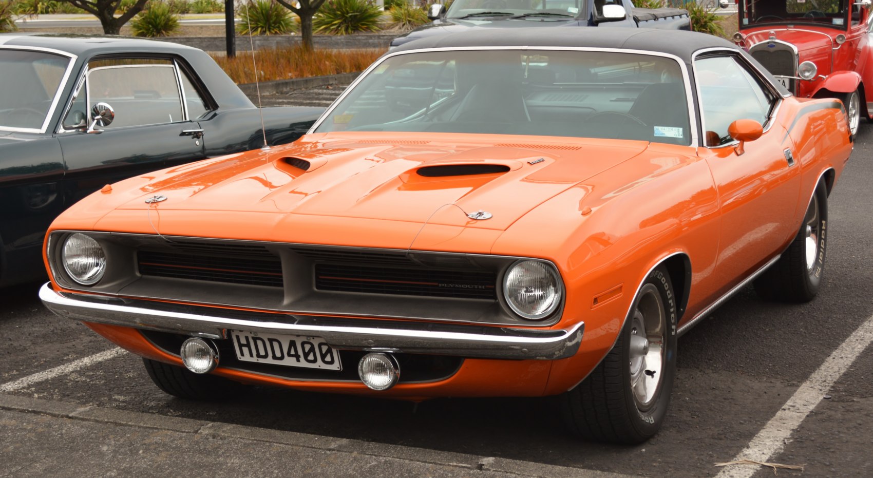 Orange vintage muscle car with black vinyl roof and front hood scoops
