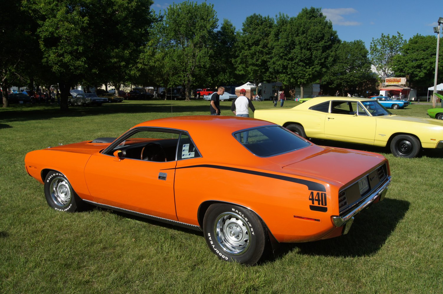 Orange muscle coupe with black 440 stripe and chrome wheels on grass.