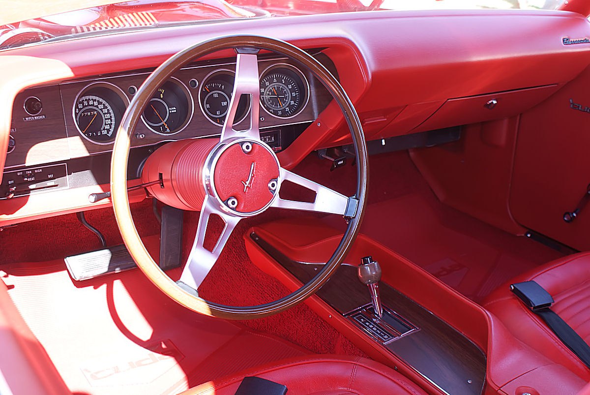 Bright red vintage interior with wooden steering wheel and classic gauges