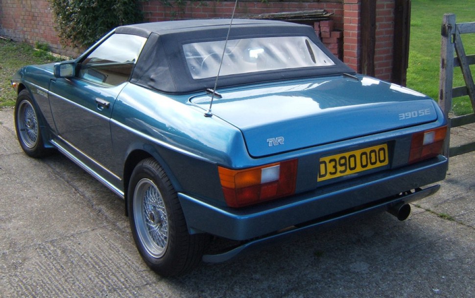 Rear and side view of a two-door sports convertible with wire wheels and soft top
