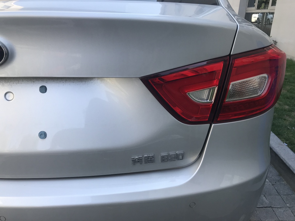 Rear tail light and trunk badge close-up on silver sedan.