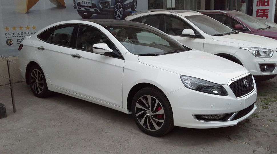 White sedan with alloy wheels and red brake calipers seen from front side angle