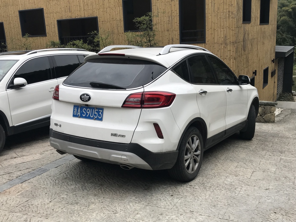 Rear and side exterior view of a white SUV with roof rails and taillights