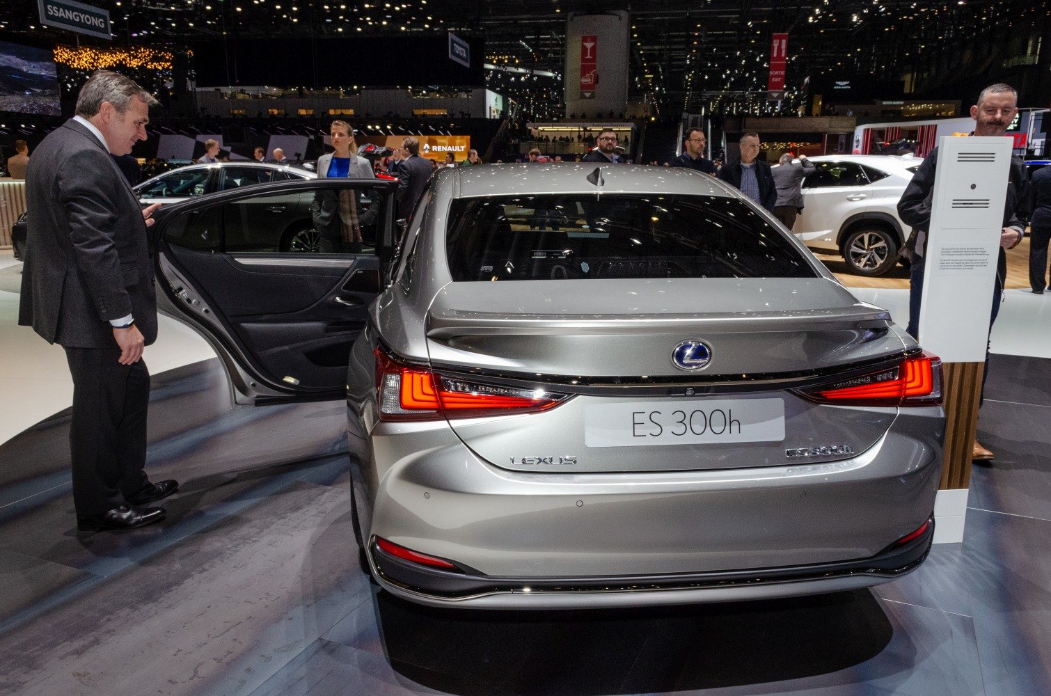 Rear view with illuminated tail lights and open rear door of a silver sedan.