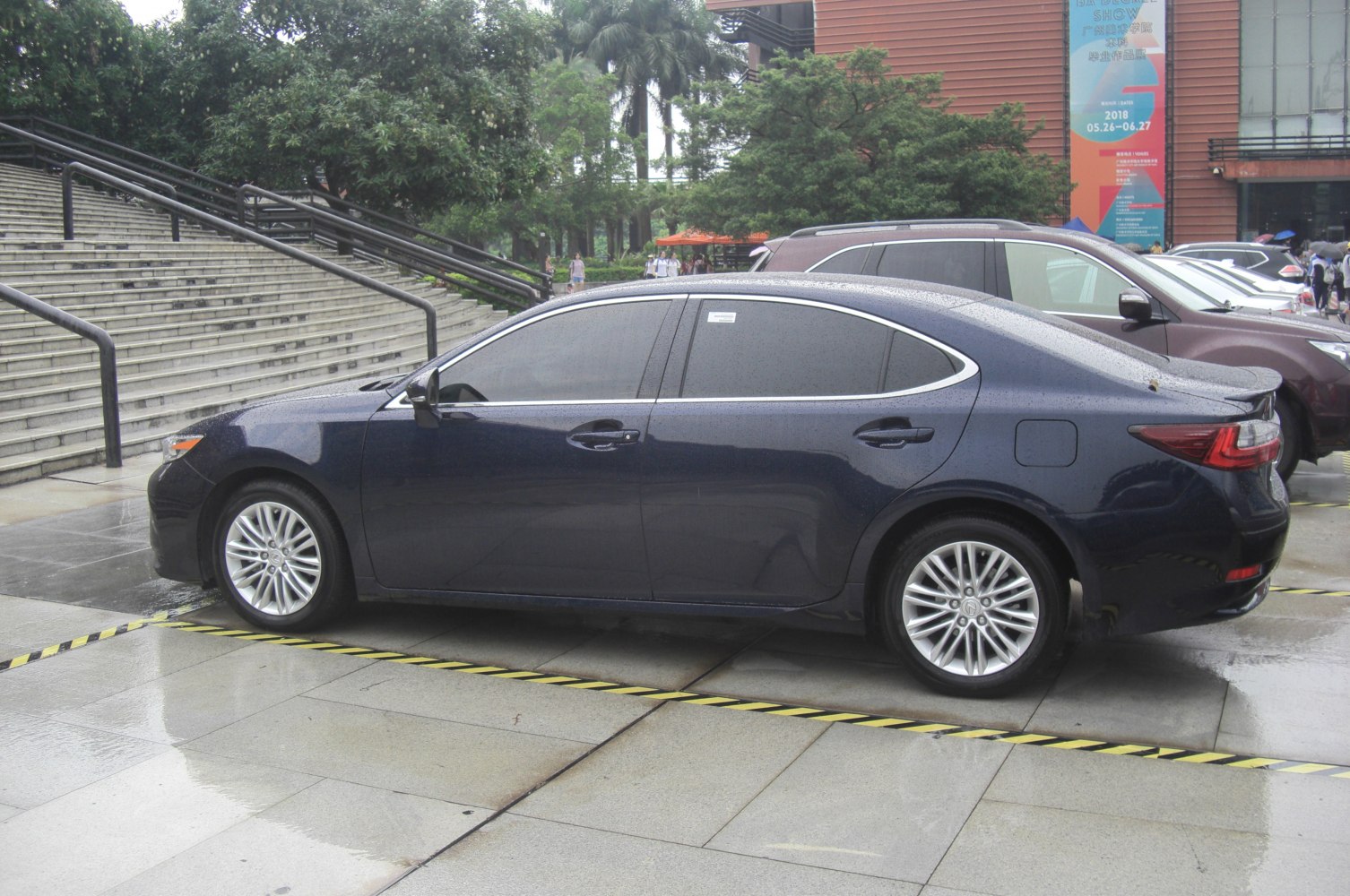 Side profile of luxury sedan with alloy wheels and tinted windows on wet pavement