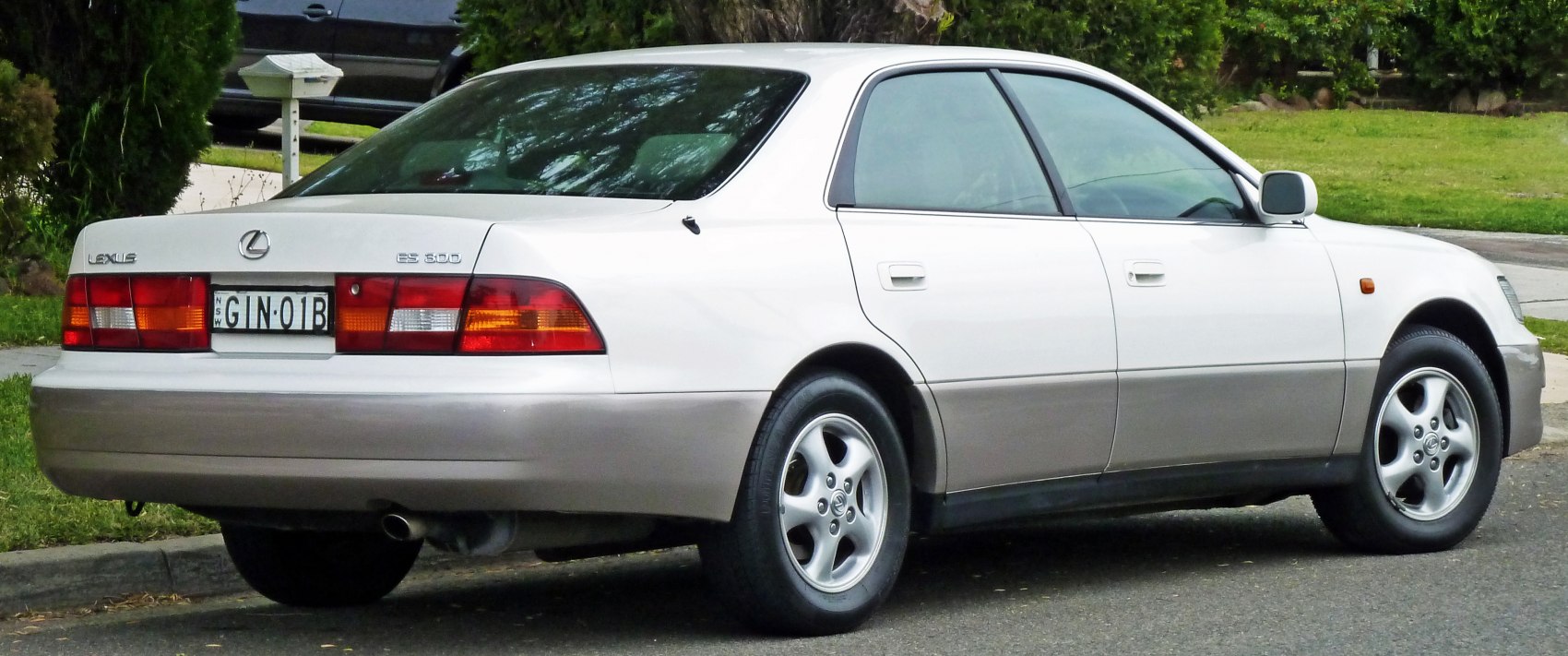 Rear-side view of a luxury sedan with alloy wheels and two-tone body