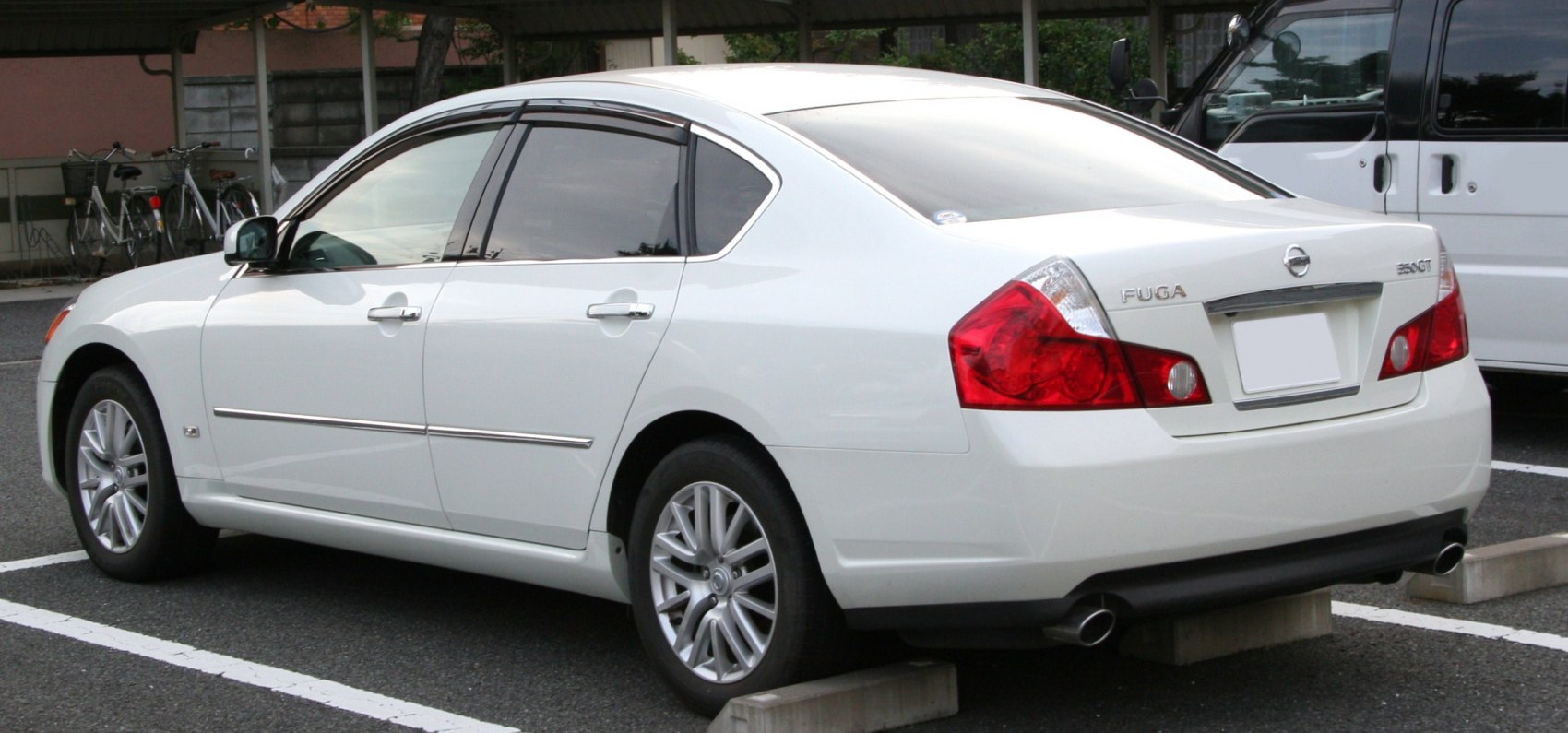 Rear side profile of white luxury sedan with distinctive tail lights and alloy wheels