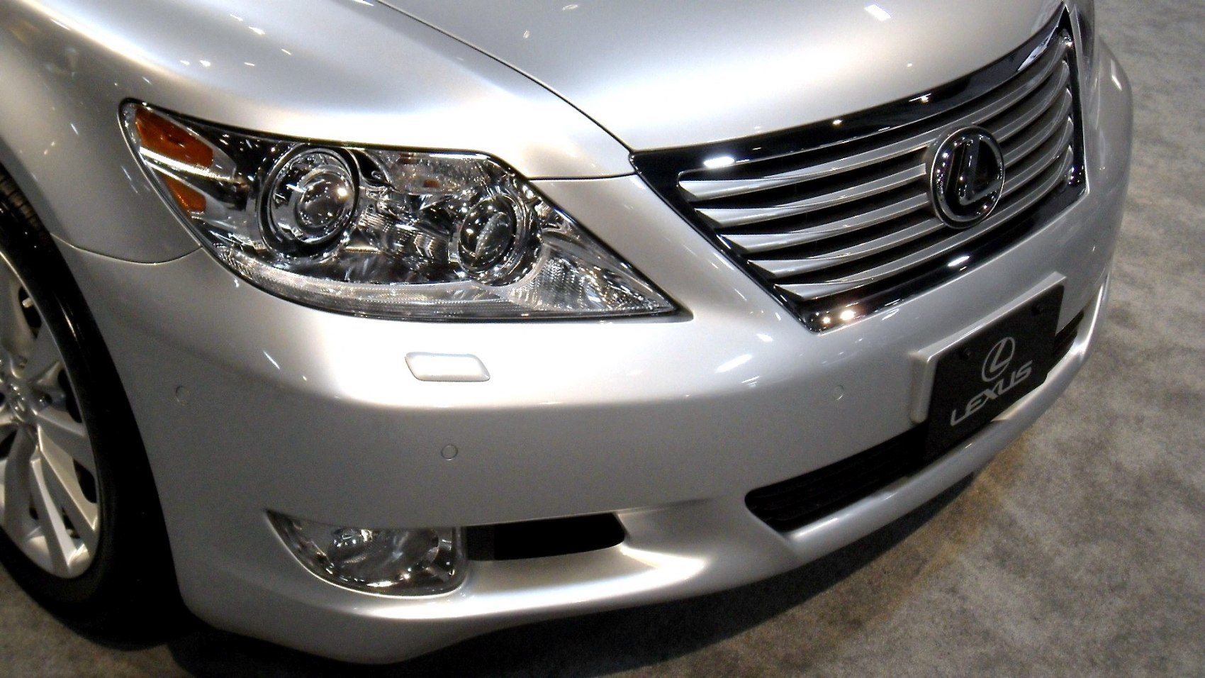 Close-up of front grille and headlights with fog lights in silver luxury sedan.
