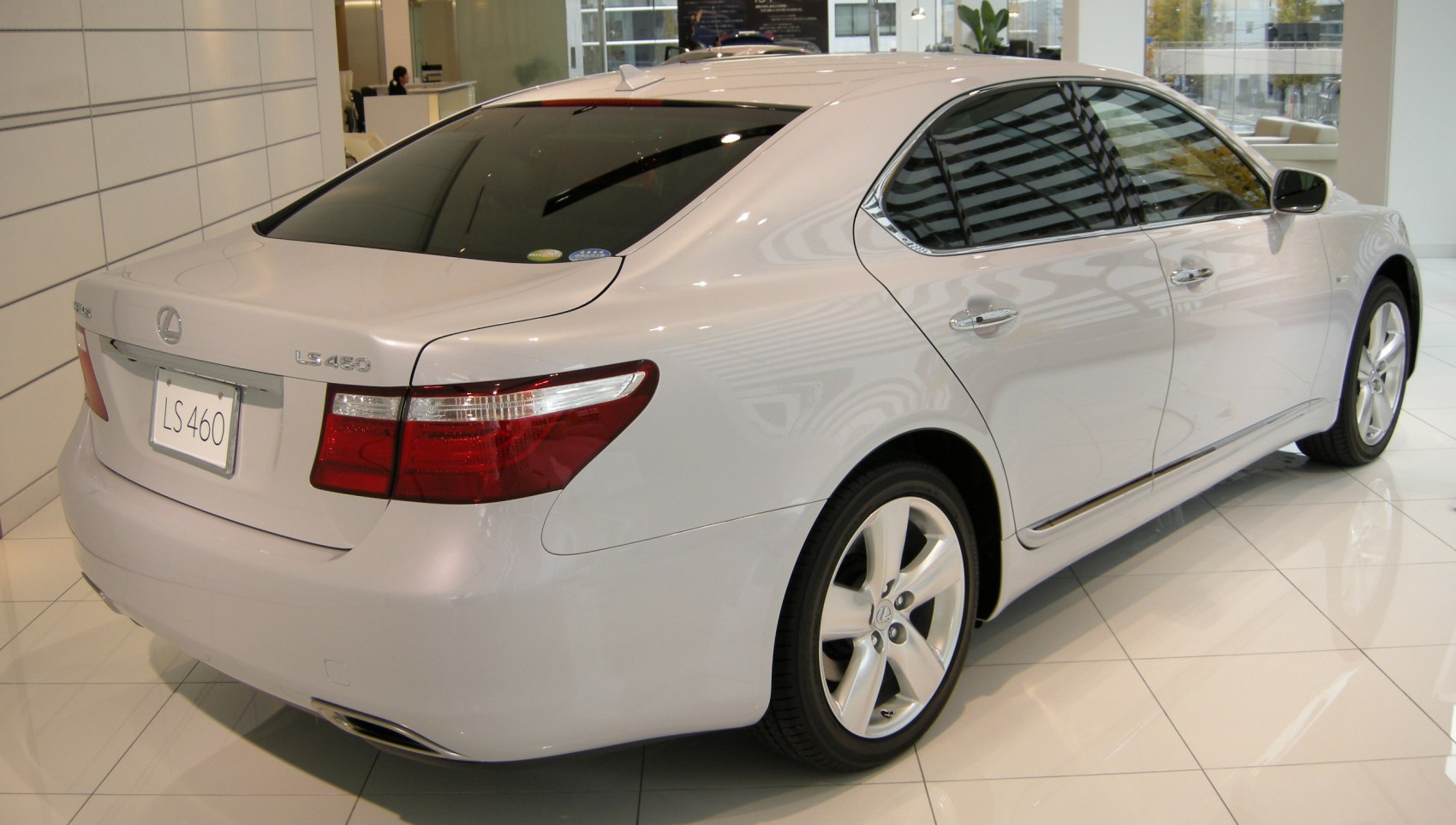 Rear side view with alloy wheels and tinted windows in showroom.