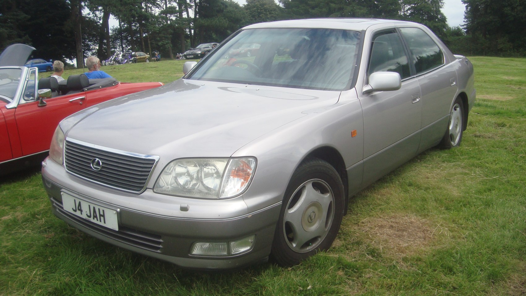 Silver luxury sedan front angle with grille and alloy wheels on grass