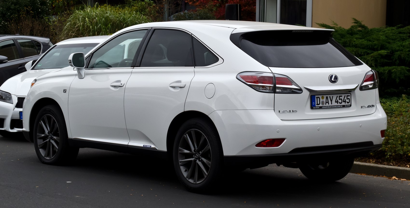 White SUV with black alloy wheels and rear spoiler, dark tinted windows