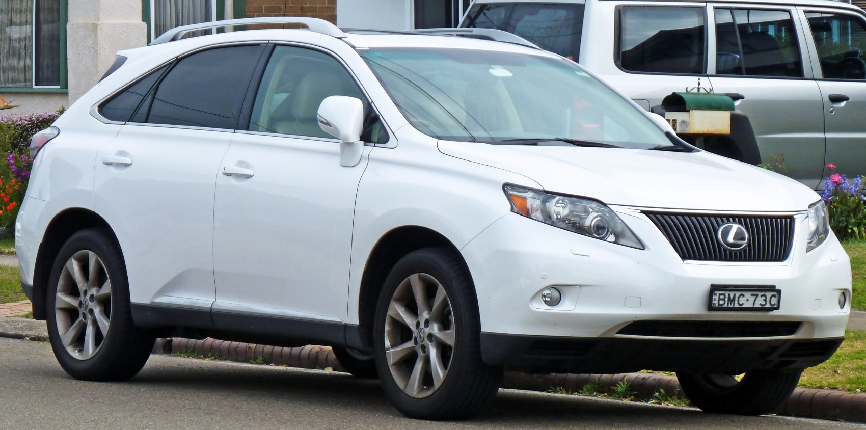 Front side view of white luxury SUV with sleek headlamps and grille
