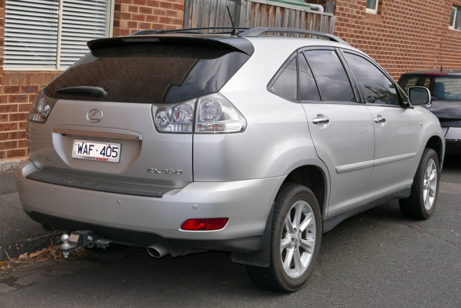 Silver SUV rear view with tail lights, tow hitch, roof rails