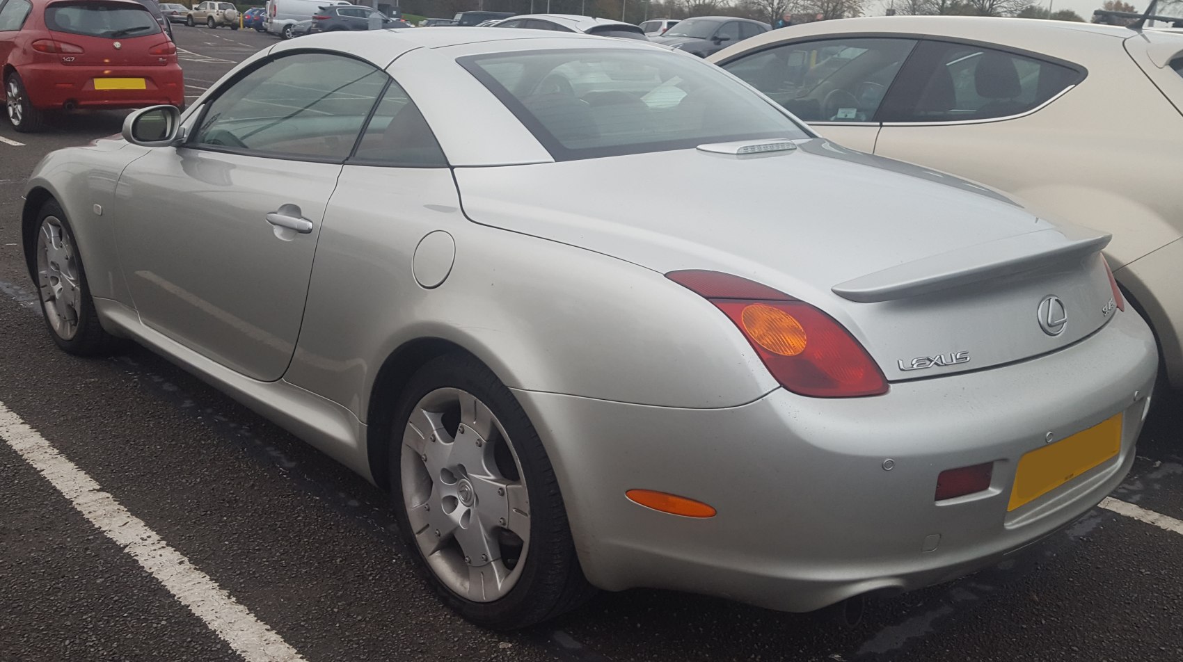Silver coupe with rear spoiler and alloy wheels parked outdoors