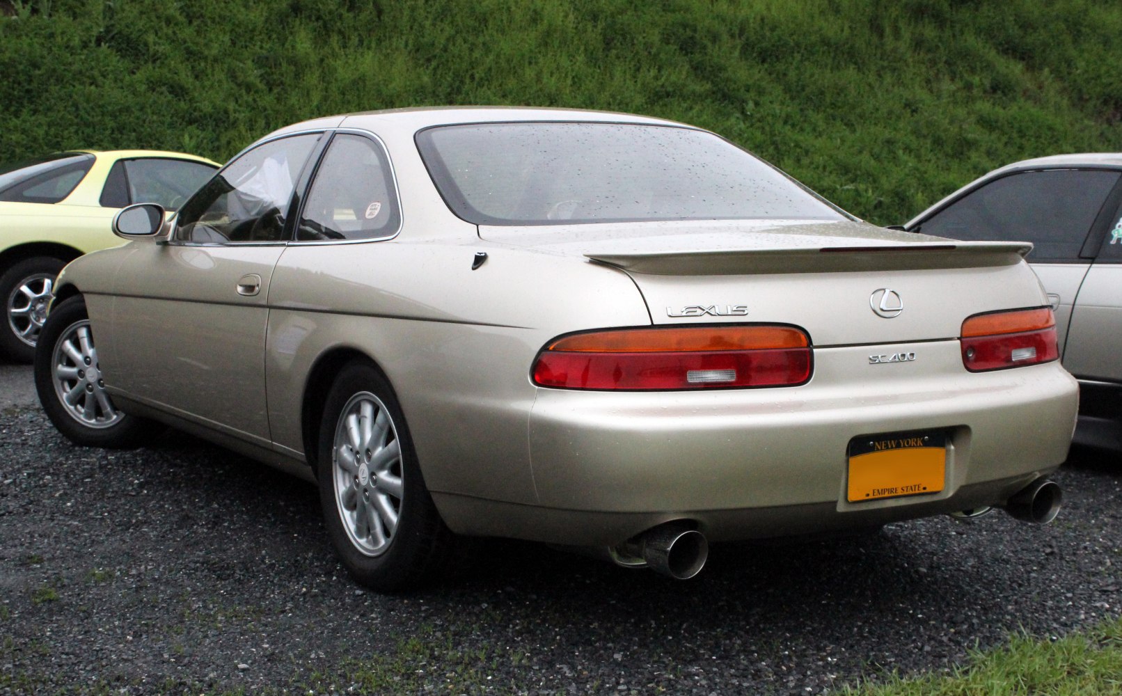 Rear view with smooth tail lights, dual exhaust, and rear spoiler.