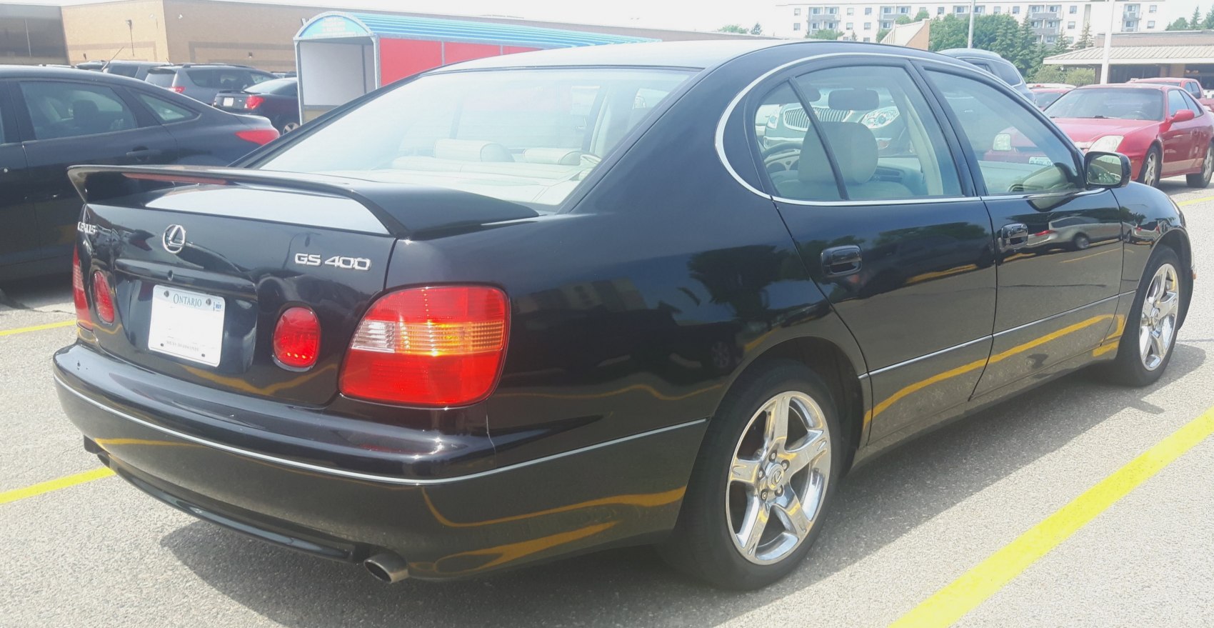 Rear side of black sedan with spoiler and chrome alloy wheels