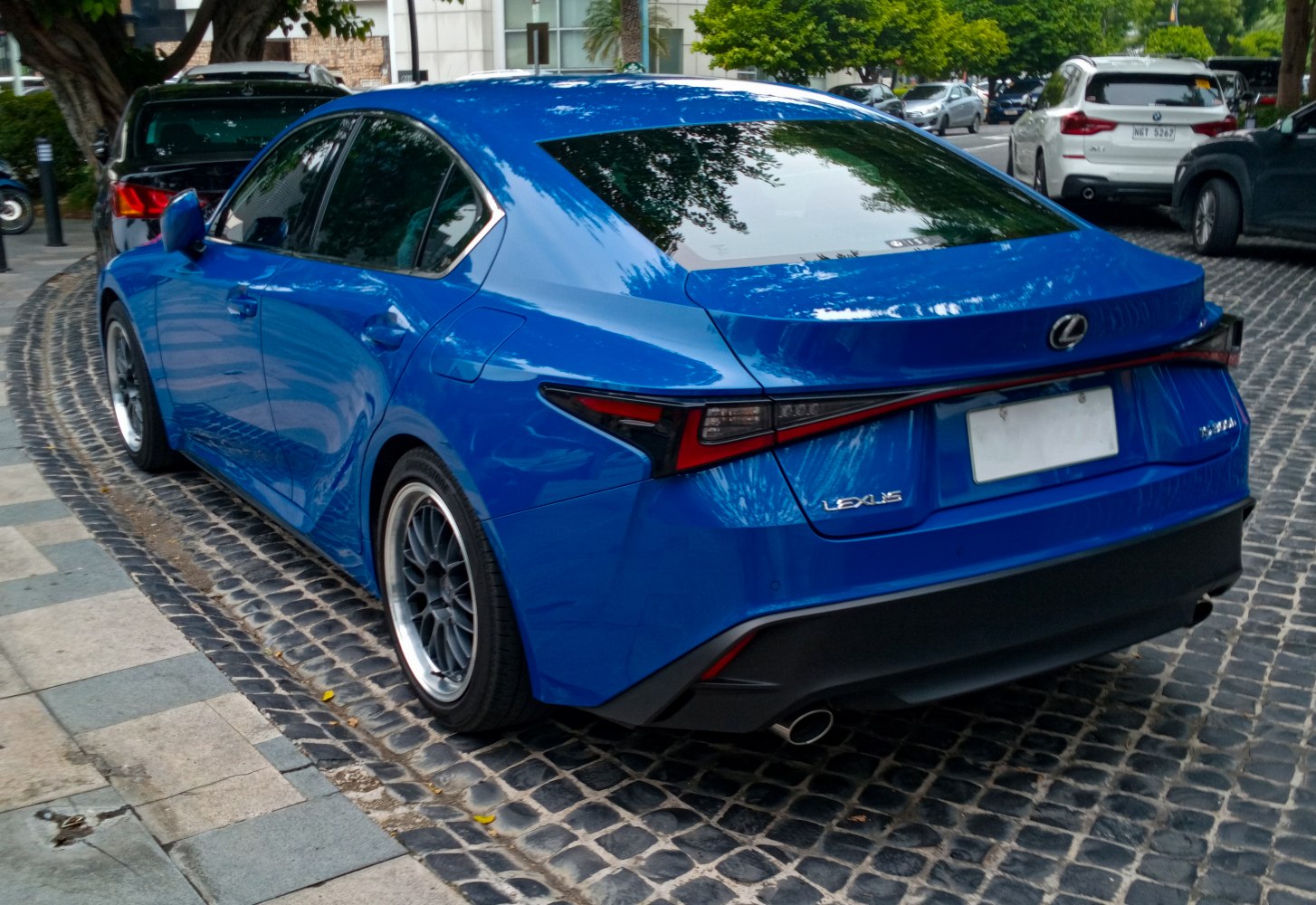 Rear view of a blue sedan with distinct taillights and dual exhausts