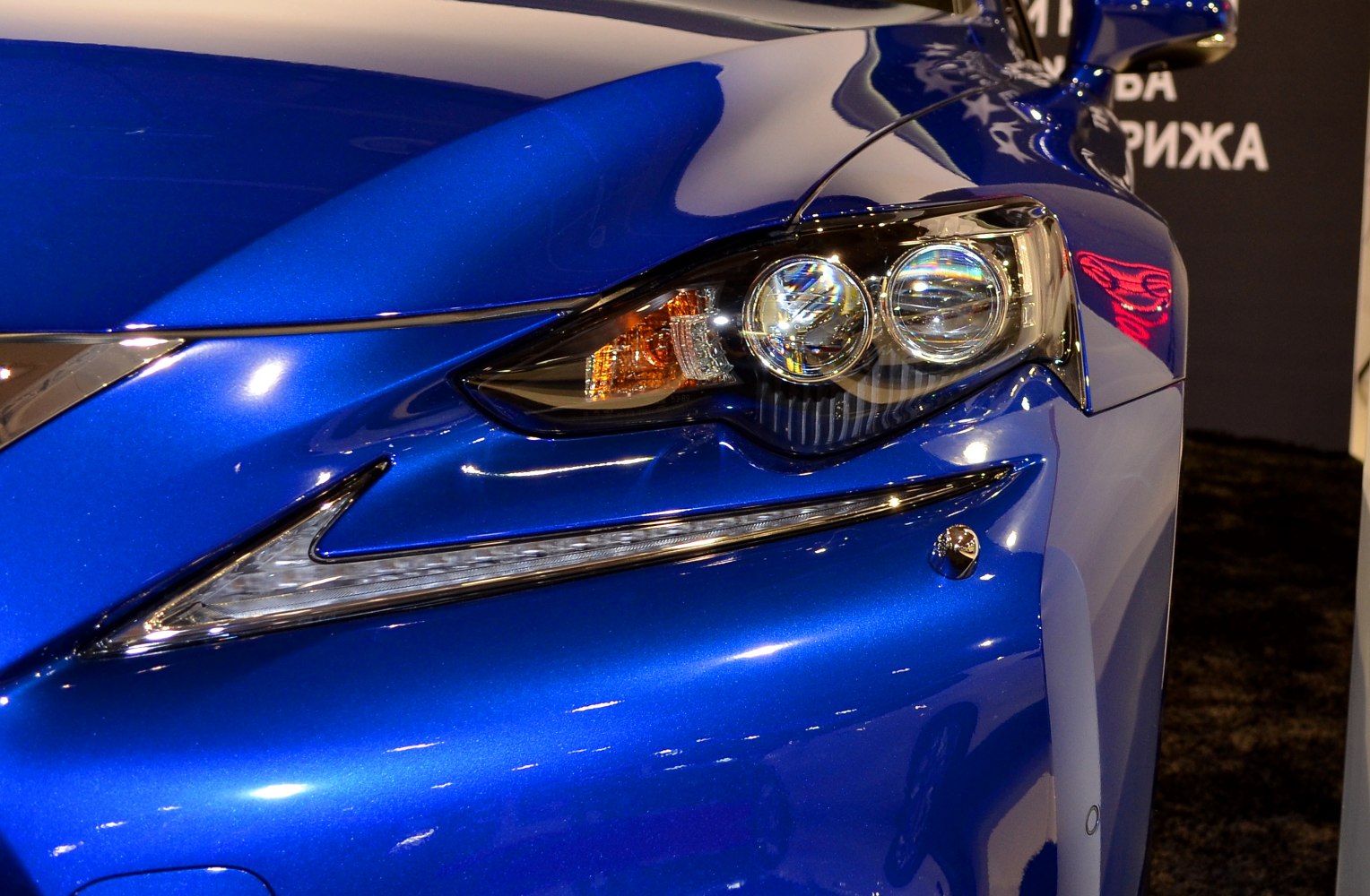 Close-up of sleek front headlight and blue painted hood
